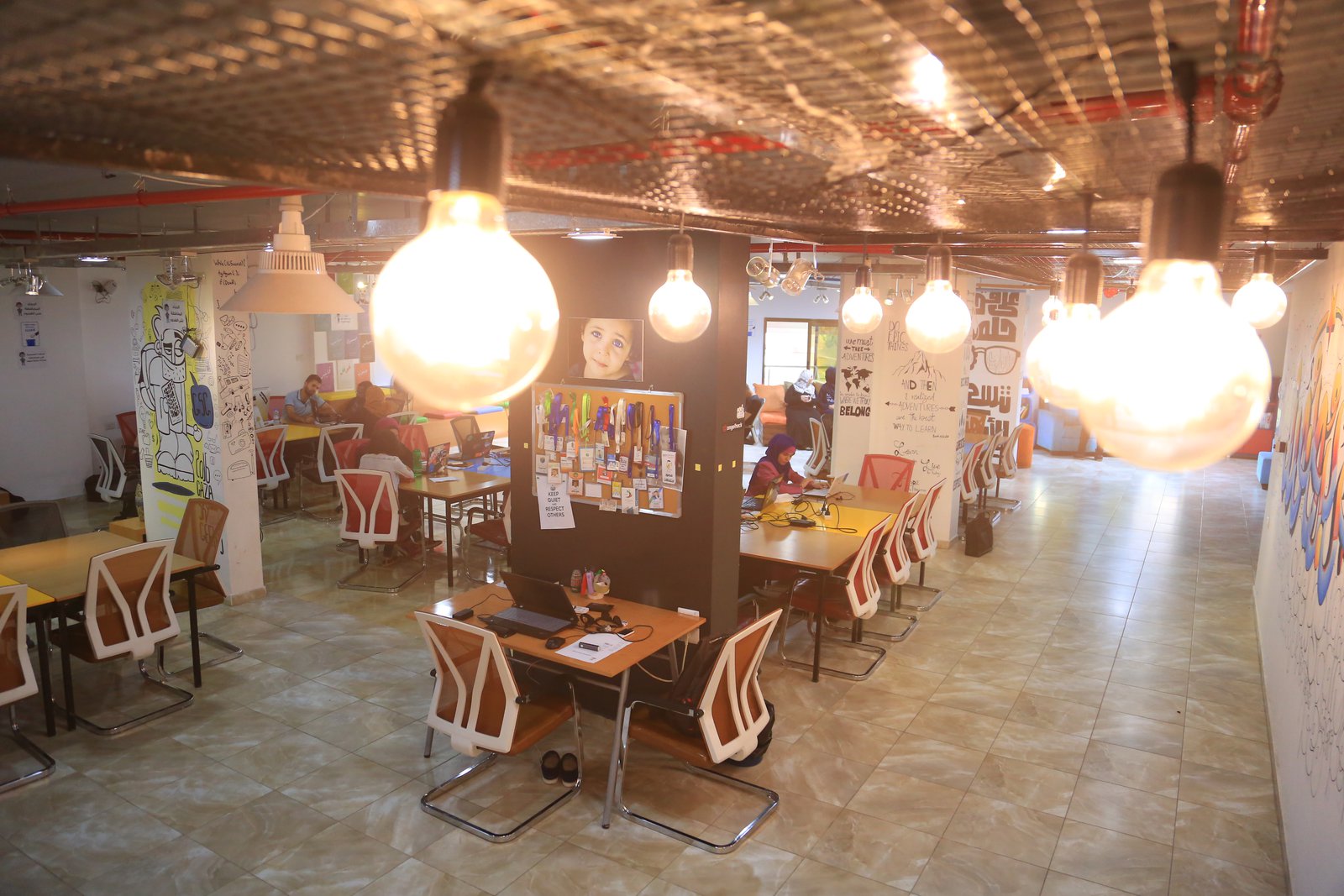 Modern coworking space with ergonomic chairs, dual 4K monitors, and leafy indoor plants